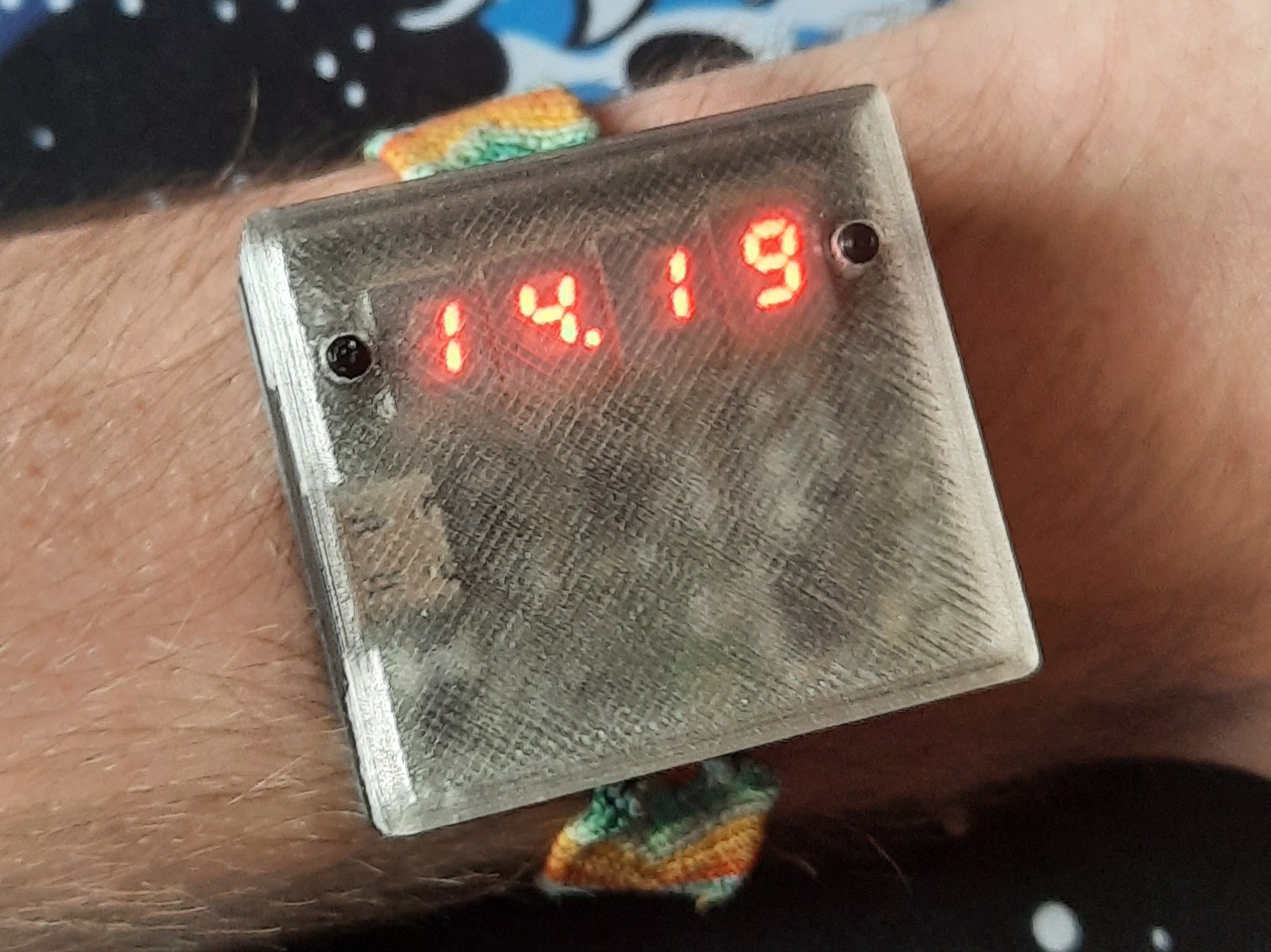 A picture of myself wearing my custom wrist watch. It's displaying the current time using four red seven segment displays.